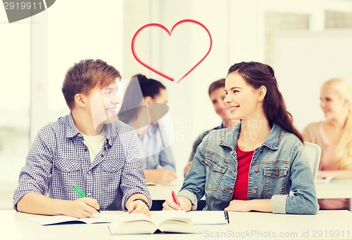 Image of two teenagers with notebooks and book at school