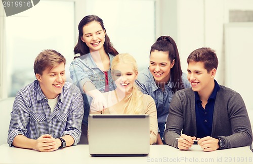 Image of smiling students looking at laptop at school