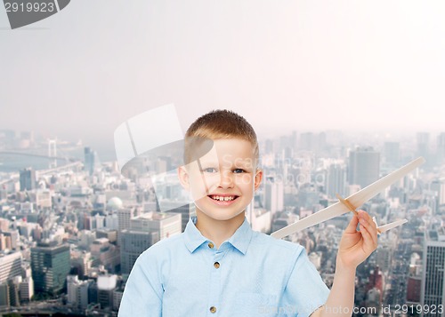 Image of smiling little boy holding a wooden airplane model