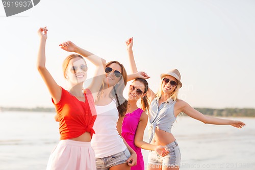 Image of group of smiling women dancing on beach