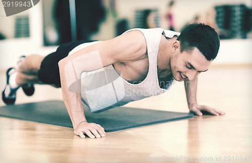 Image of smiling man doing push-ups in the gym