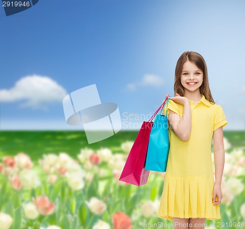 Image of smiling little girl in dress with shopping bags