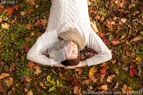 Image of smiling young man lying on ground in autumn park