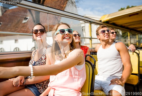 Image of group of smiling friends traveling by tour bus