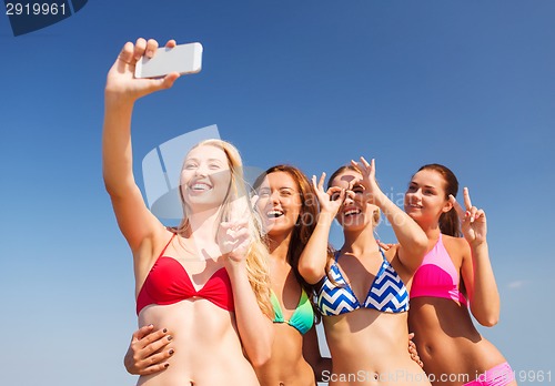 Image of group of smiling women making selfie on beach