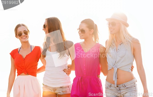 Image of group of smiling women in sunglasses on beach