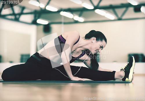 Image of smiling woman stretching on mat in the gym
