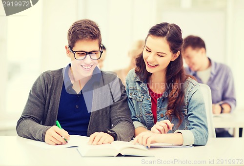 Image of two teenagers with notebooks and book at school