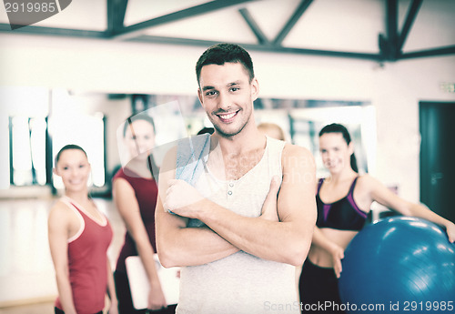 Image of smiling man standing in front of the group in gym