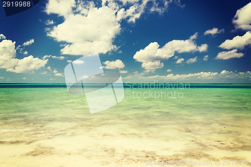 Image of blue sea or ocean, white sand and sky with clouds