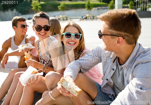 Image of group of smiling friends sitting on city square