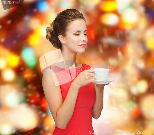 Image of smiling woman in red dress with cup of coffee