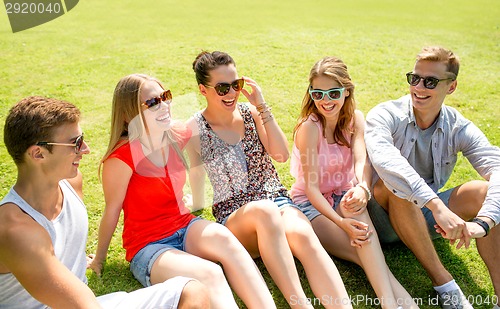 Image of group of smiling friends outdoors sitting in park