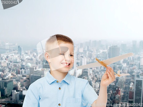 Image of smiling little boy holding a wooden airplane model