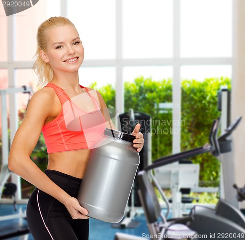 Image of smiling sporty woman with jar of protein