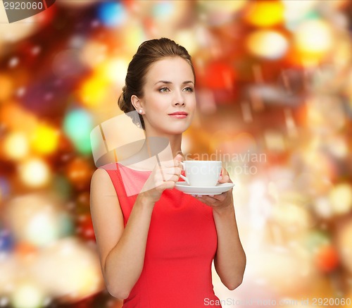 Image of smiling woman in red dress with cup of coffee