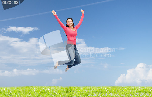 Image of smiling young woman jumping in air