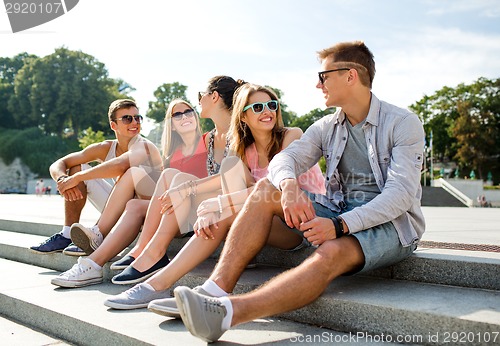 Image of group of smiling friends sitting on city street