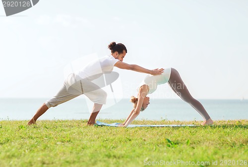 Image of smiling couple making yoga exercises outdoors