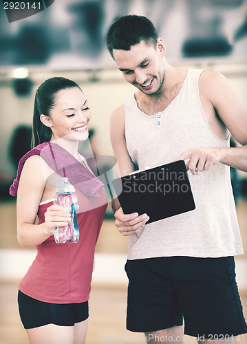 Image of smiling male trainer with woman in the gym