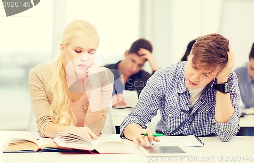 Image of tired students with tablet pc, books and notebooks