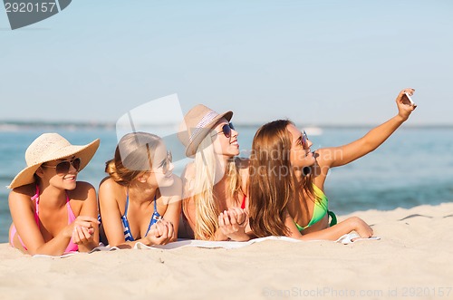 Image of group of smiling women with smartphone on beach