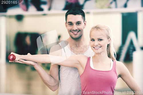 Image of male trainer with woman working out with dumbbell