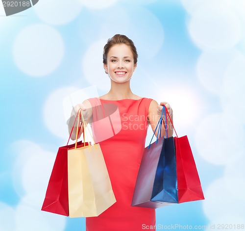 Image of smiling elegant woman in dress with shopping bags