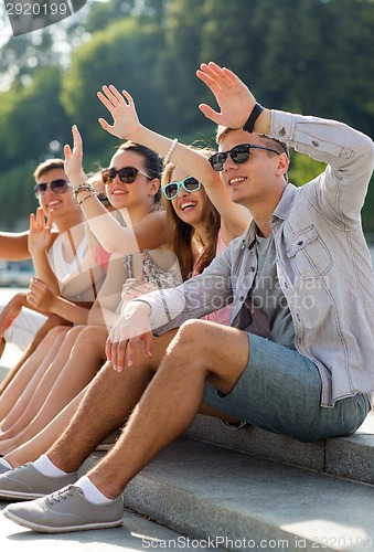 Image of group of smiling friends sitting on city street