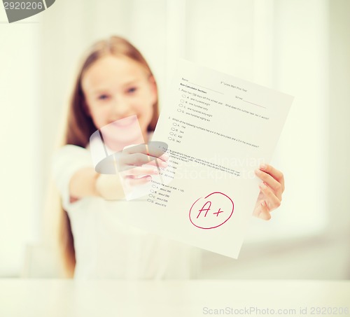 Image of smiling little student girl with test and A grade