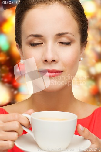 Image of smiling woman in red dress with cup of coffee