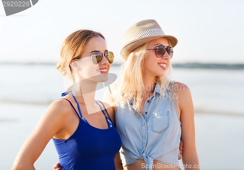 Image of two smiling women in sunglasses on beach