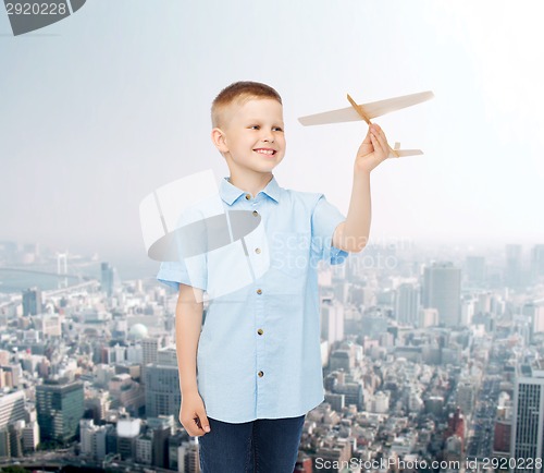 Image of smiling little boy holding a wooden airplane model