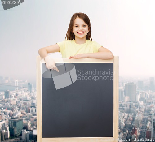 Image of happy little girl pointing finger to blackboard