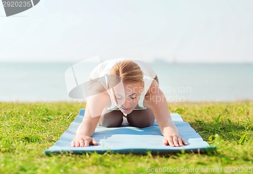 Image of young woman making yoga exercises outdoors