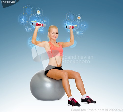 Image of woman with dumbbells sitting on fitness ball