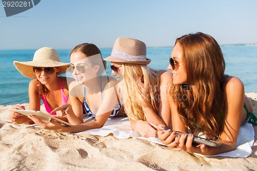 Image of group of smiling young women with tablets on beach