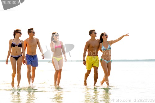 Image of smiling friends in sunglasses on summer beach