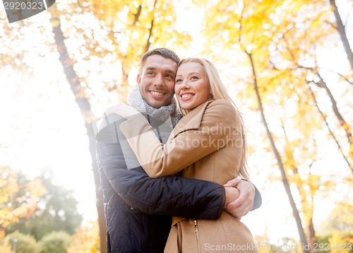 Image of smiling couple hugging in autumn park