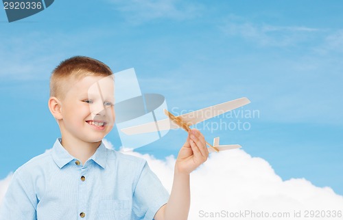 Image of smiling little boy holding a wooden airplane model