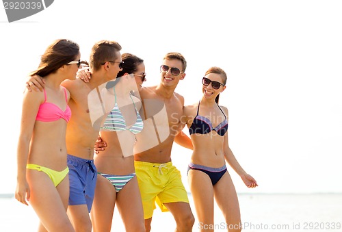 Image of smiling friends in sunglasses on summer beach