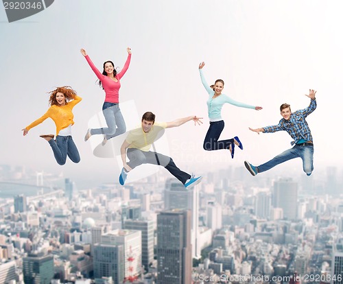 Image of group of smiling teenagers jumping in air