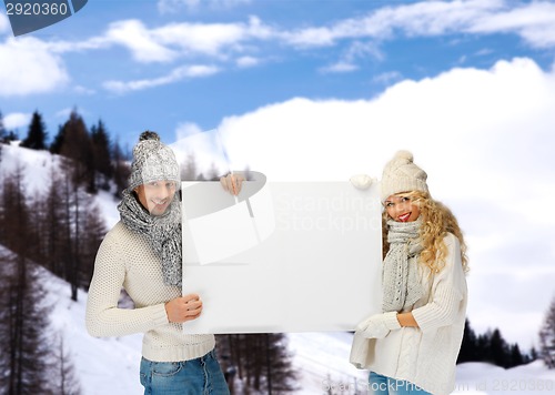 Image of smiling couple in winter clothes with blank board