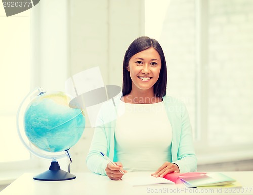 Image of teacher with globe and notepad at school