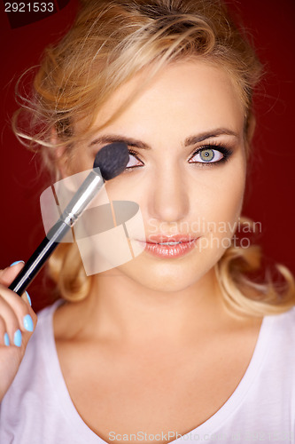 Image of Beautiful blond woman applying eye makeup