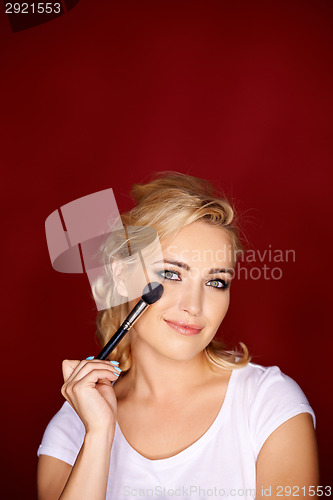 Image of Beautiful blond woman applying eye makeup