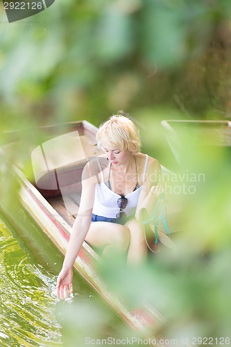 Image of Woman relaxing on the vintage wooden boat.