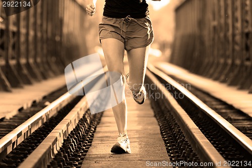 Image of Active female athlete running on railaway tracks.