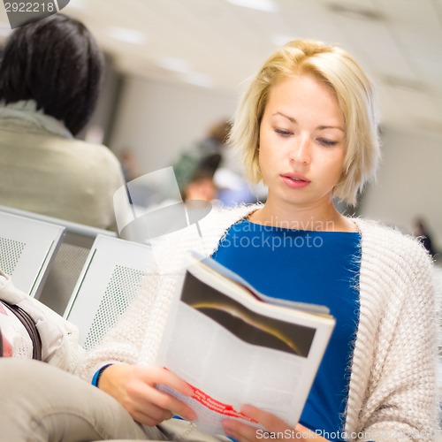 Image of Woman reading a magazine while waiting.