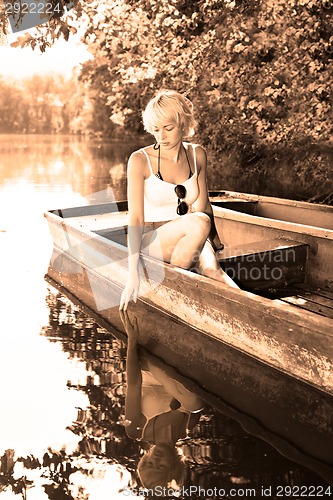 Image of Woman relaxing on the vintage wooden boat.